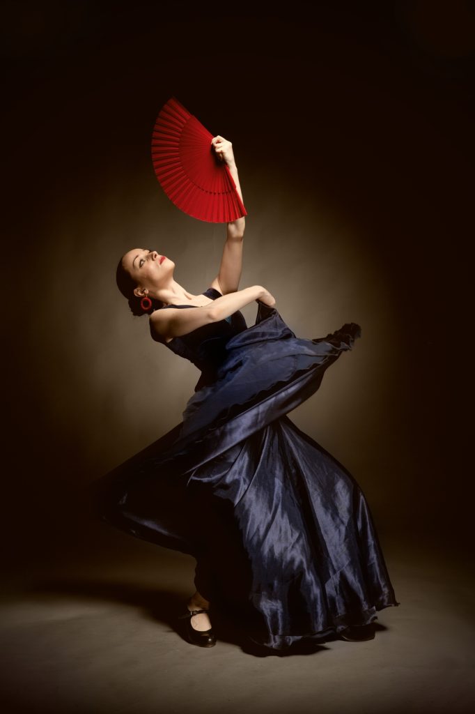 young woman dancing flamenco on black
